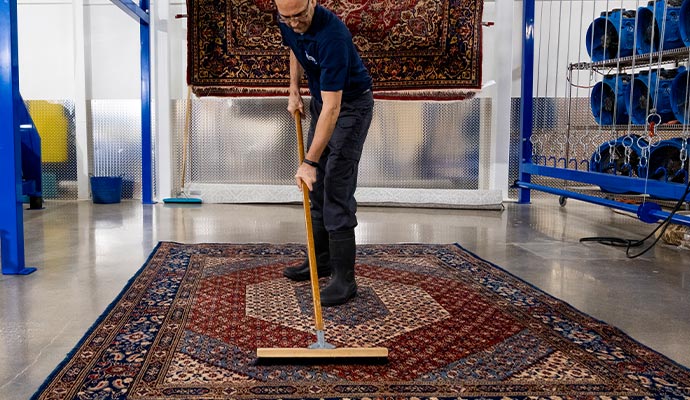 worker claning afghan rug